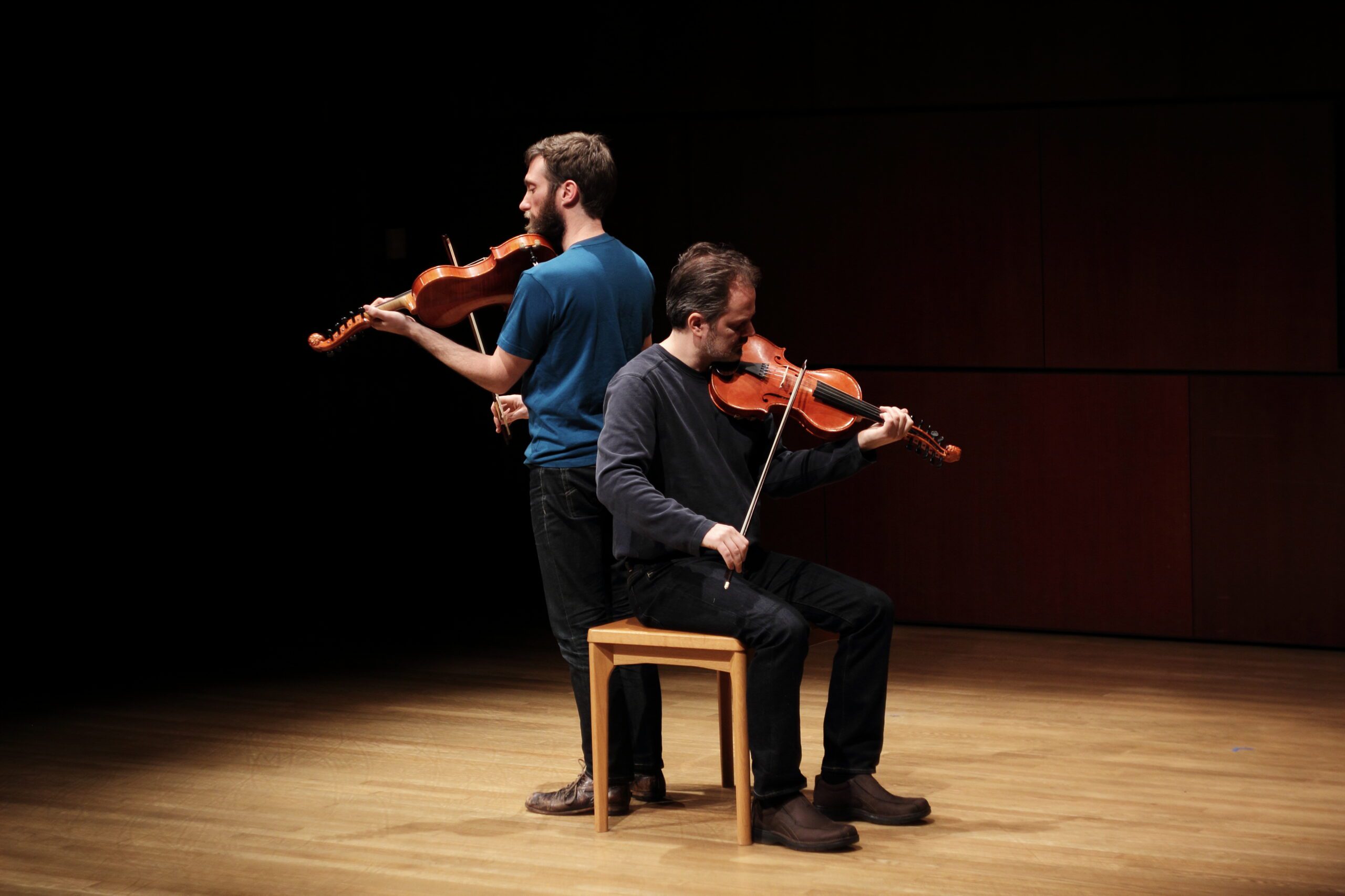 photo of Caoimhín Ó Raghallaigh and Dan Trueman, playing instruments on a darkened stage.