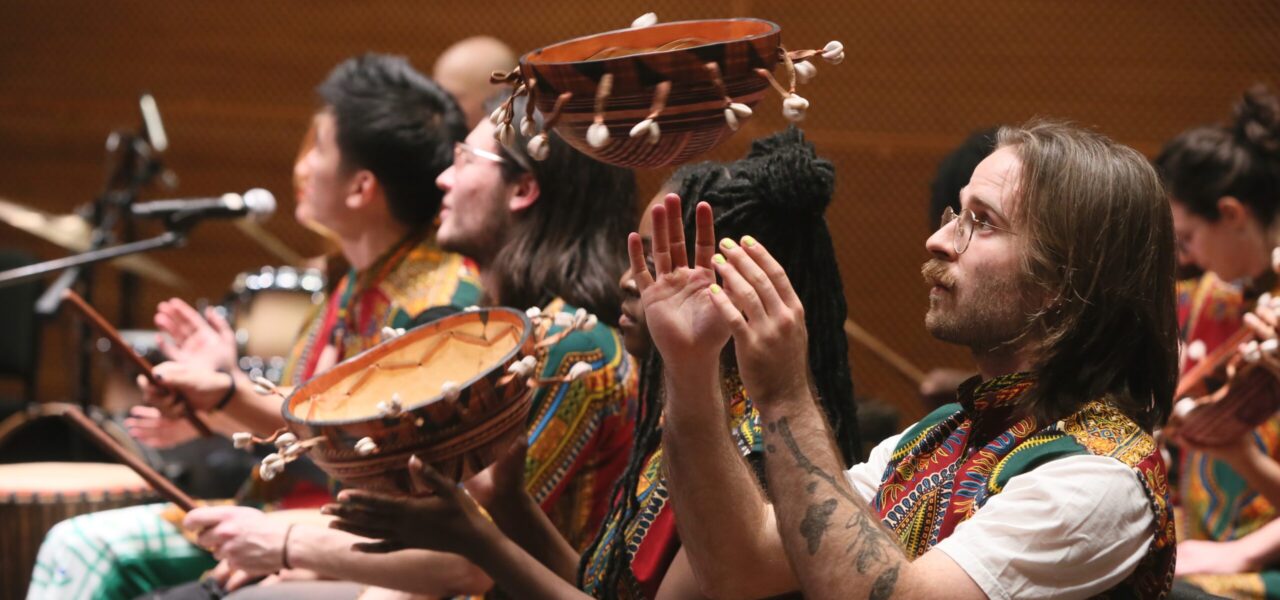 photo of African Music Ensemble performing , with performers playing African drums or clapping