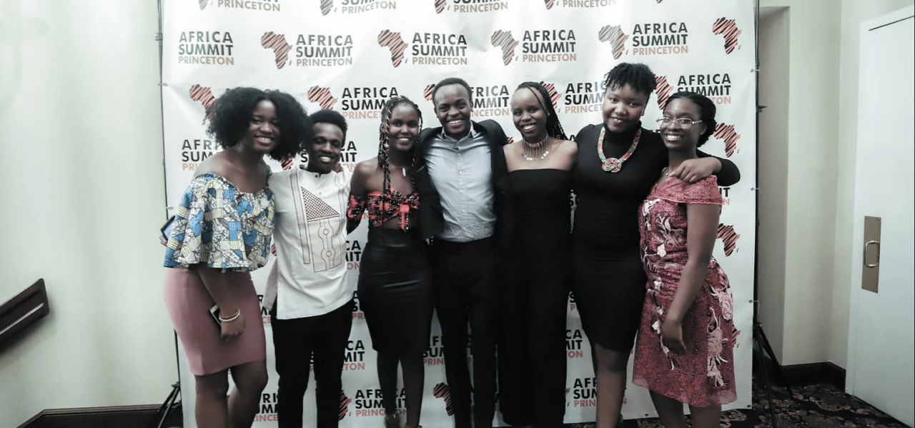 7 people smiling and standing in front of a backdrop curtain that reads "Africa Summit Princeton"