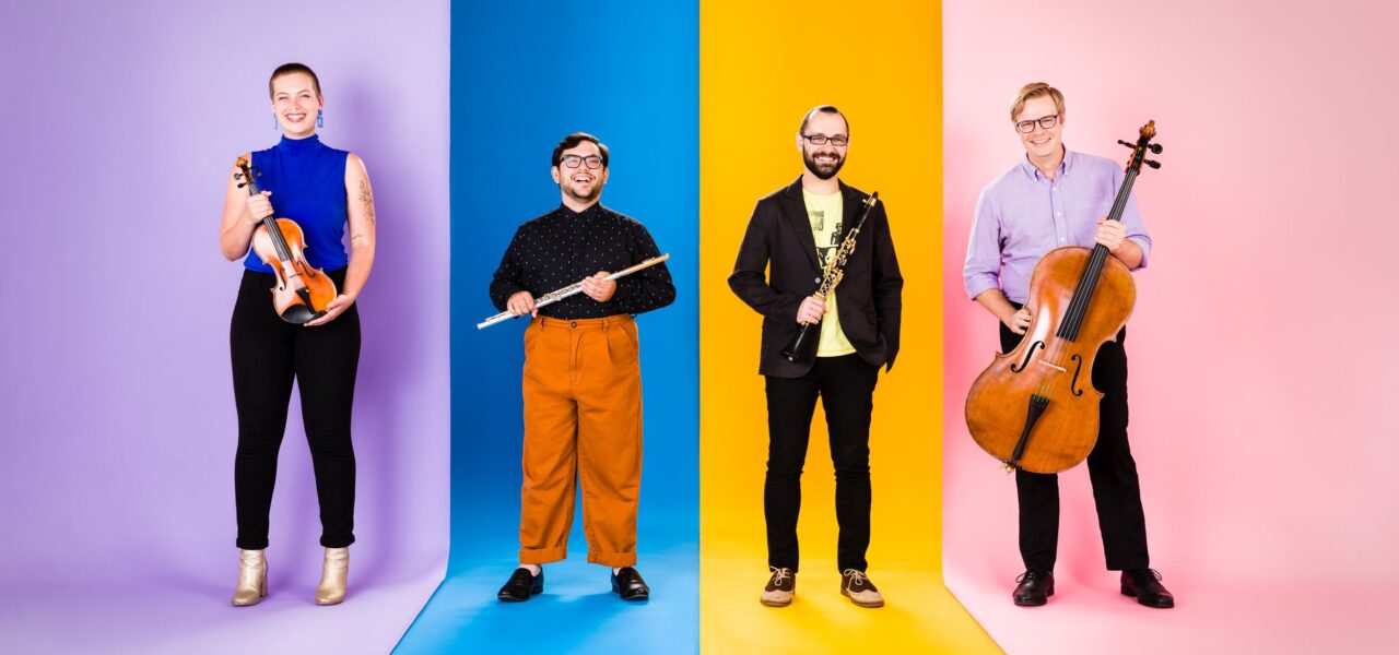 A group of musicians standing in front of a multi-colored background